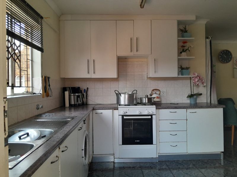 A functional kitchen featuring white cabinetry, laminate countertops, a built-in oven with hob, and tiled flooring, offering a practical layout for daily use.