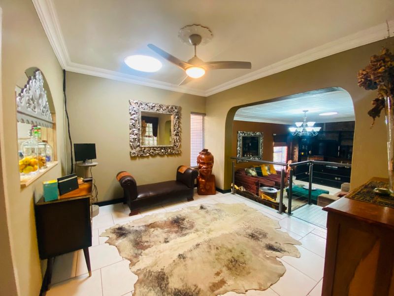 An open-plan living area featuring tiled flooring, a ceiling fan, and a glass balustrade overlooking a sunken lounge space.