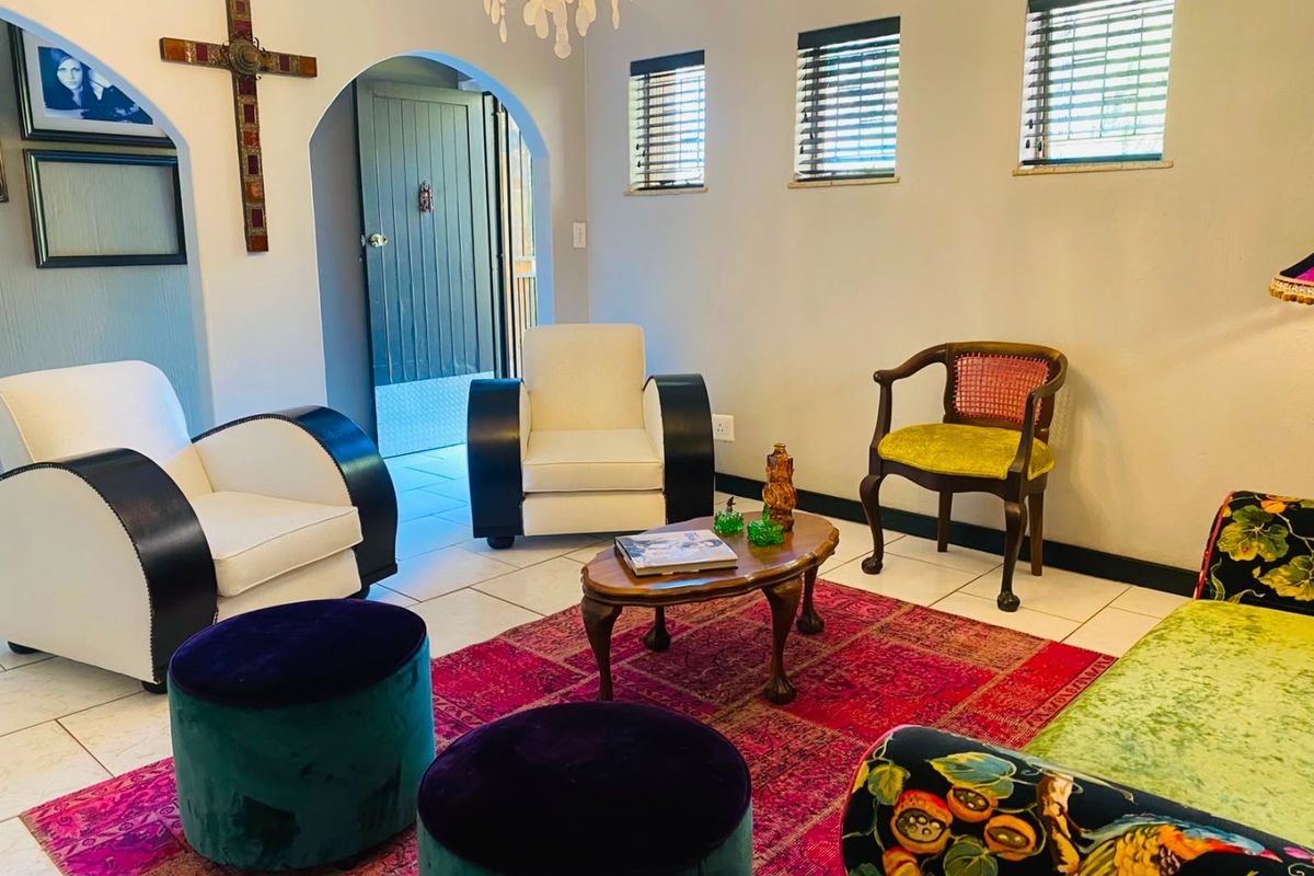 A living room featuring tiled flooring, an arched entryway, and natural light through multiple windows with venetian blinds.