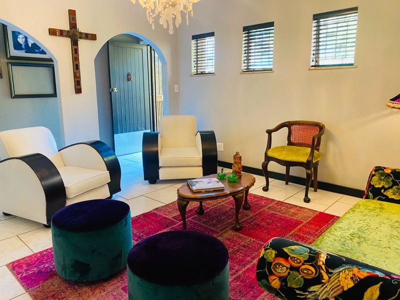 A living room featuring tiled flooring, an arched entryway, and natural light through multiple windows with venetian blinds.