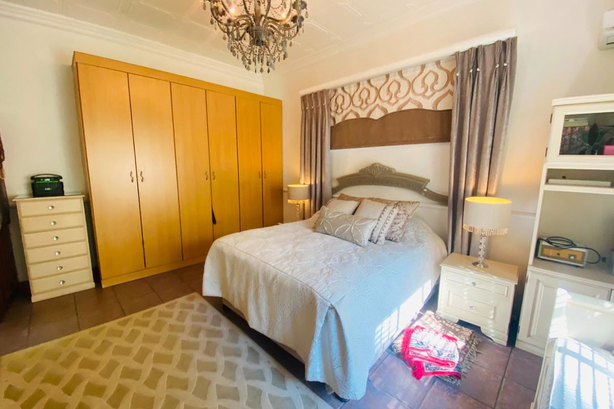 A bedroom featuring built-in wooden wardrobes, tiled flooring, and a decorative ceiling, offering a functional space with classic design elements.