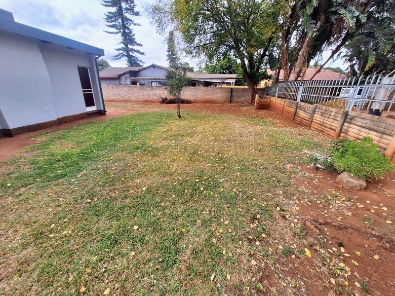 A rear garden area featuring a lawn, retaining wall, and perimeter fencing, offering potential for landscaping and outdoor improvement.