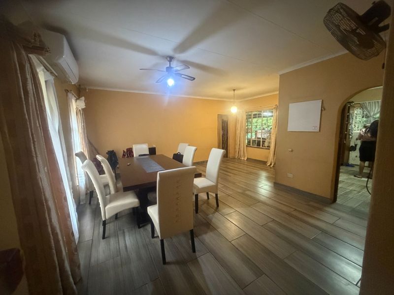 Dining room featuring tiled flooring, a ceiling fan, and a split-system air conditioner, with an arched doorway leading to adjacent living spaces.