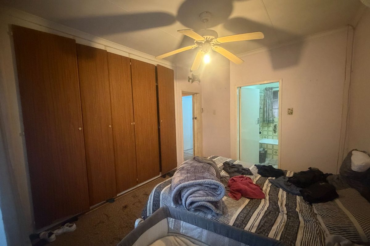 A bedroom featuring built-in wooden cupboards, a ceiling fan, and direct access to an en-suite bathroom.