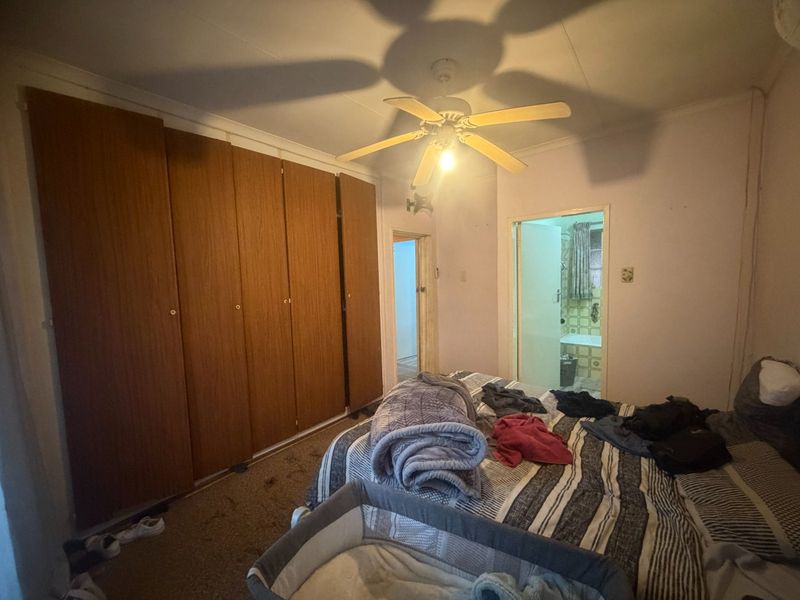 A bedroom featuring built-in wooden cupboards, a ceiling fan, and direct access to an en-suite bathroom.