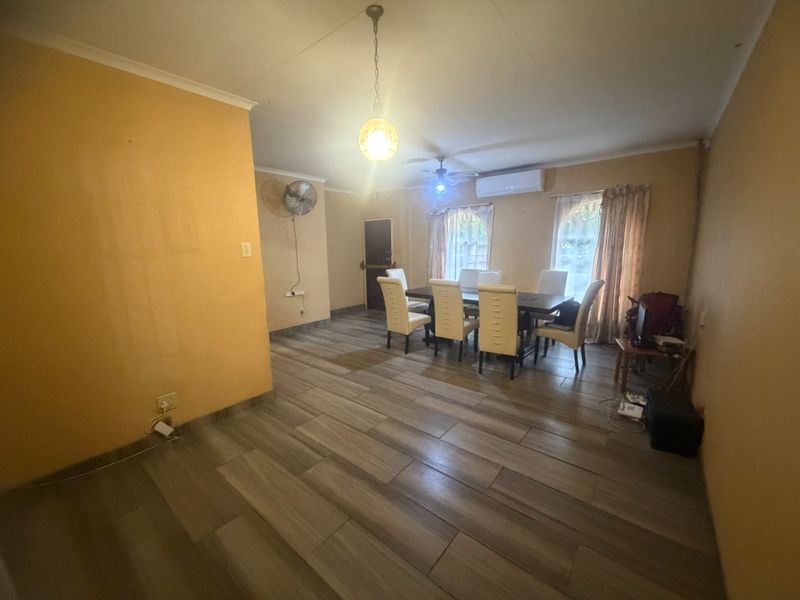 Spacious dining area featuring wood-look tile flooring, a ceiling fan, and a wall-mounted air conditioning unit.