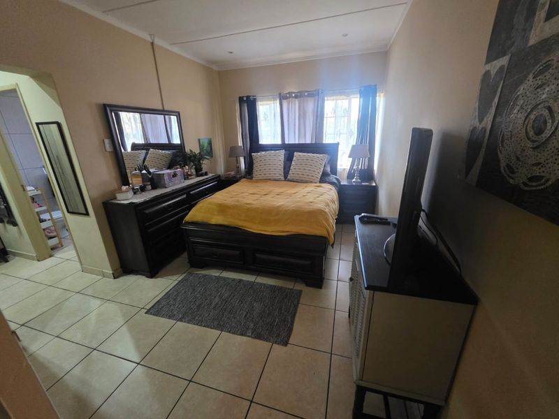A bedroom featuring tiled flooring, coved ceilings, and recessed lighting, with an adjacent view into a bathroom area.