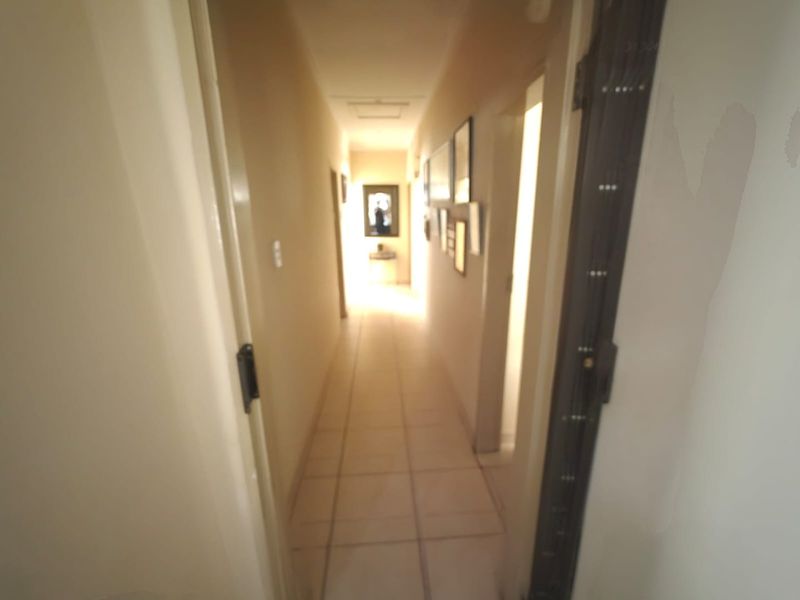 A narrow residential hallway featuring tiled flooring, connecting various rooms within the property.