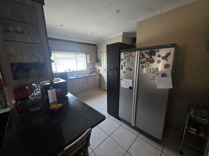 Functional kitchen featuring granite countertops, laminate cabinetry, and tiled flooring, offering a practical layout with ample storage and preparation space.