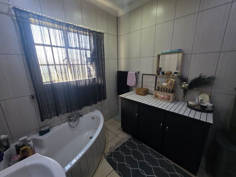 A functional bathroom featuring a corner bathtub, tiled wall finishes, and a built-in vanity cabinet with storage.