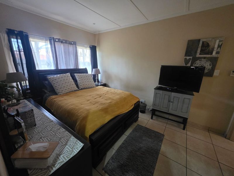 A functional bedroom featuring tiled flooring and neutral wall finishes, providing a comfortable and well-lit sleeping space.