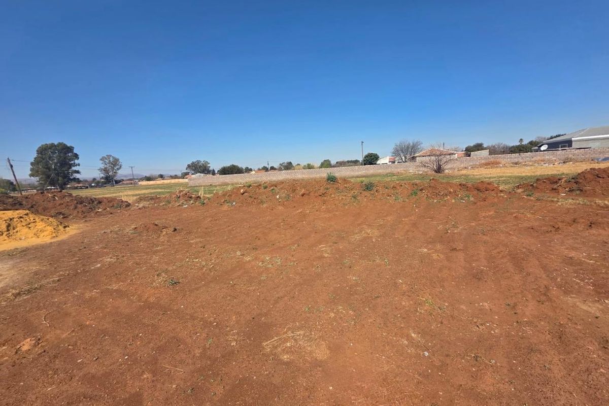 An undeveloped plot of land featuring cleared earth and a perimeter boundary wall, offering a blank canvas for future construction.