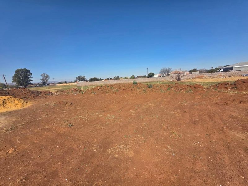 An undeveloped plot of land featuring cleared earth and a perimeter boundary wall, offering a blank canvas for future construction.