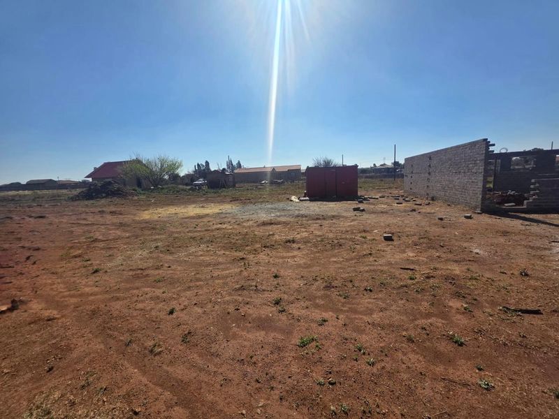A large, undeveloped plot of land featuring an unfinished boundary wall and open space, offering significant potential for future development or landscaping.