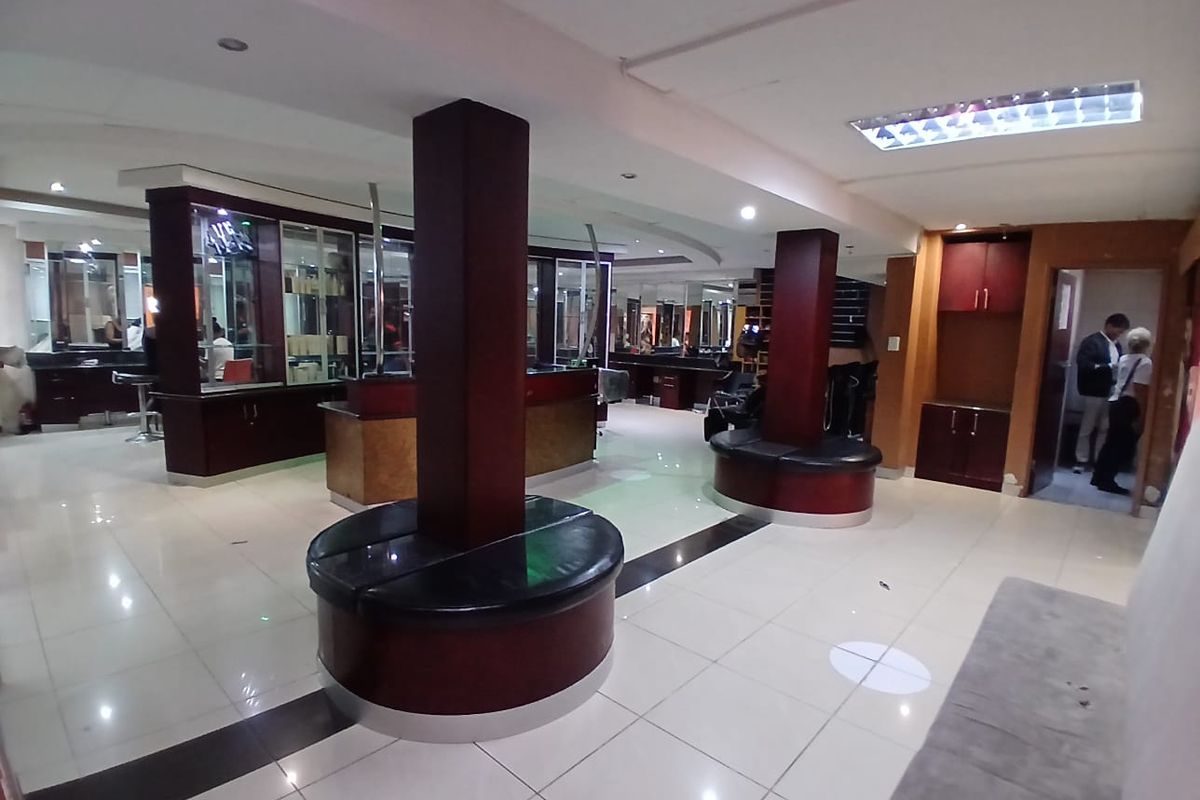 Open plan commercial space featuring tiled flooring, structural columns with integrated seating, and built-in cabinetry, suitable for a salon or retail environment.