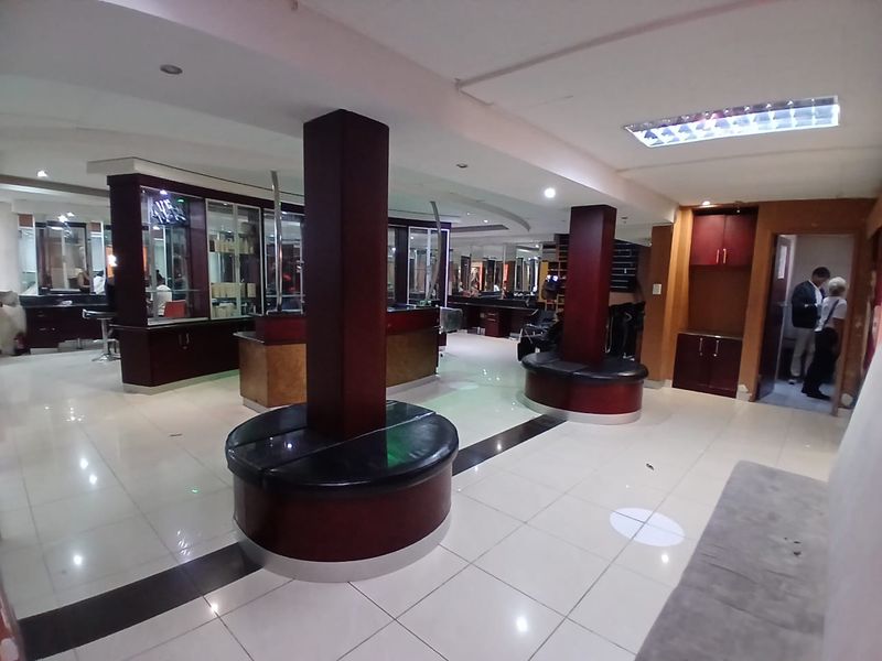 Open plan commercial space featuring tiled flooring, structural columns with integrated seating, and built-in cabinetry, suitable for a salon or retail environment.
