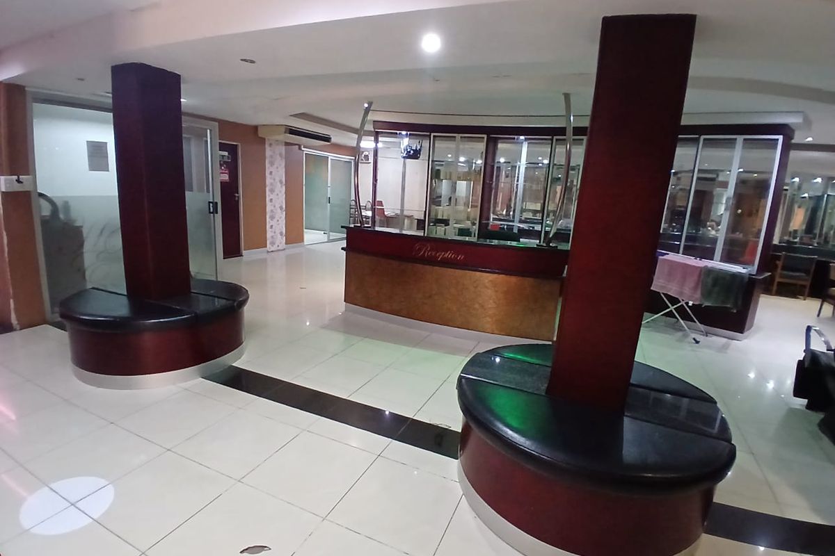 Commercial reception area featuring a built-in desk, integrated circular seating, tiled flooring, and glass partitions, providing a functional entry space for clients.