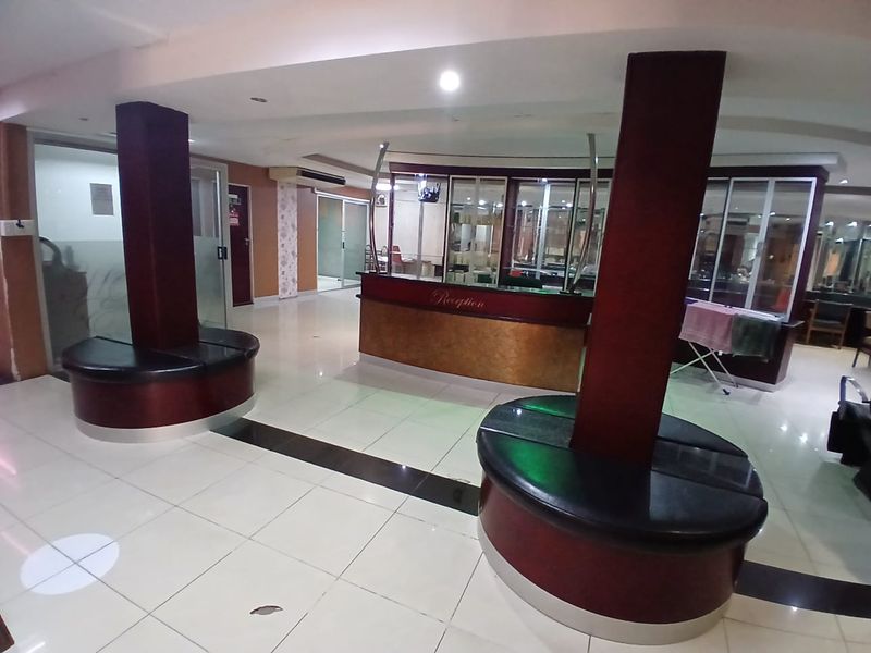 Commercial reception area featuring a built-in desk, integrated circular seating, tiled flooring, and glass partitions, providing a functional entry space for clients.