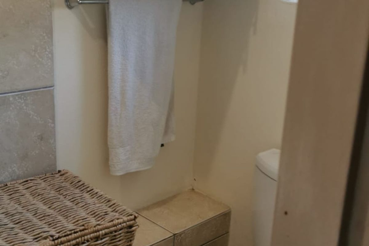 A compact bathroom featuring tiled flooring, wall-mounted storage cabinetry, and a standard toilet.