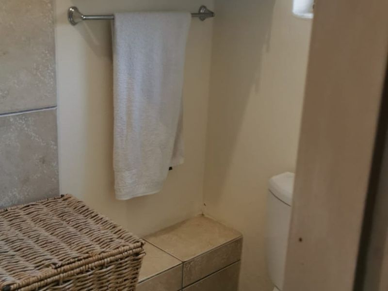 A compact bathroom featuring tiled flooring, wall-mounted storage cabinetry, and a standard toilet.
