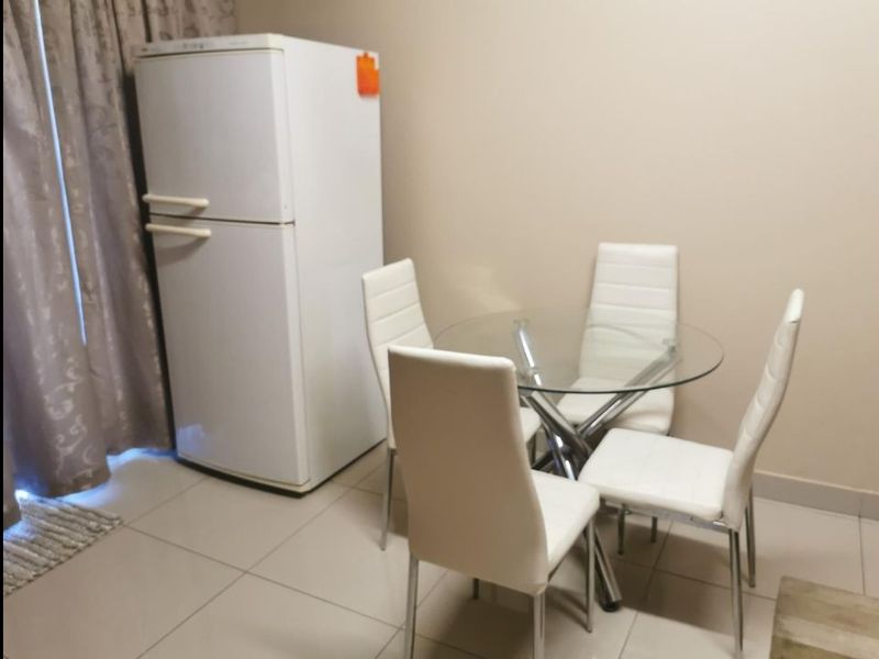 A simple dining area featuring neutral wall tones and tiled flooring, providing a functional space for meals.