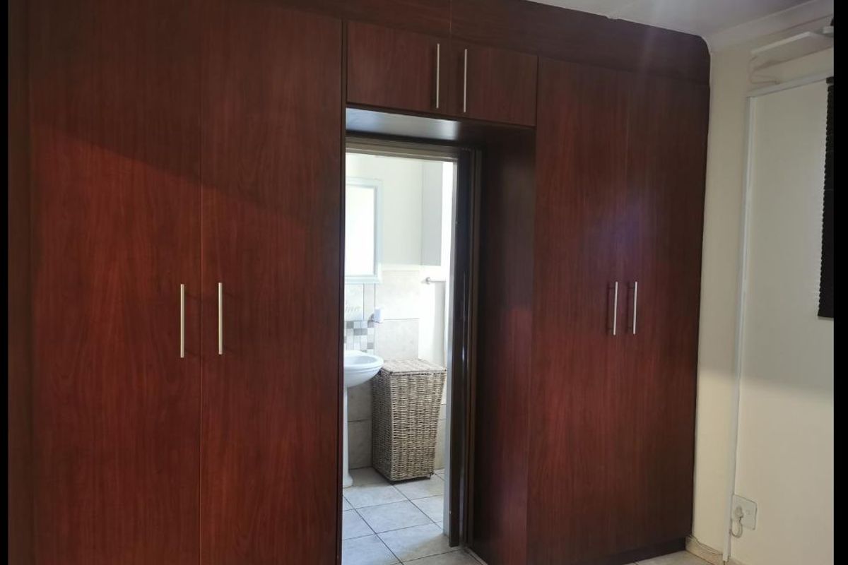 Bedroom featuring extensive dark wood built-in cupboards with a direct view into an adjoining bathroom.