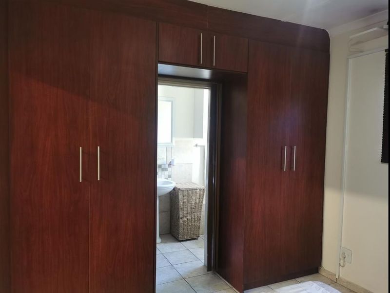 Bedroom featuring extensive dark wood built-in cupboards with a direct view into an adjoining bathroom.