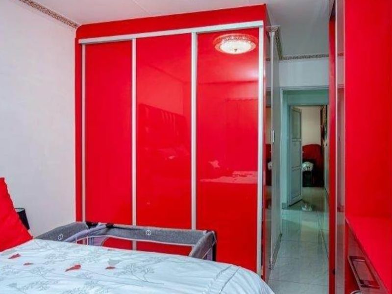 Bedroom featuring high-gloss red built-in wardrobes and tiled flooring, providing ample storage space within the apartment.