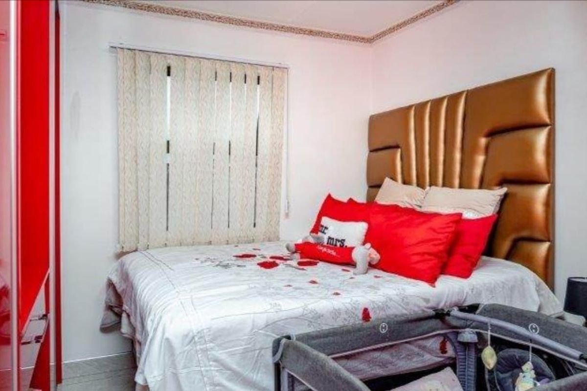 A bedroom featuring tiled flooring, vertical blinds, and a built-in wardrobe, providing a functional space with neutral wall finishes.