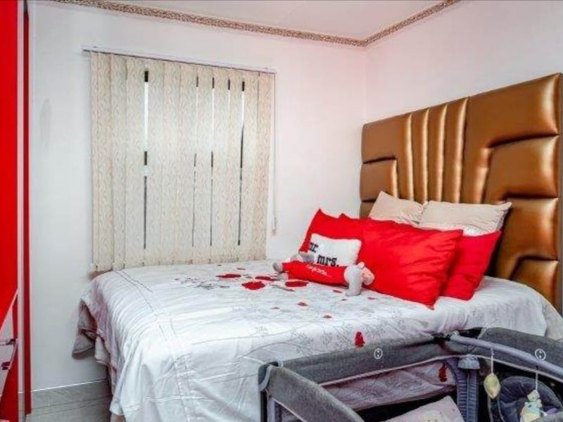 A bedroom featuring tiled flooring, vertical blinds, and a built-in wardrobe, providing a functional space with neutral wall finishes.