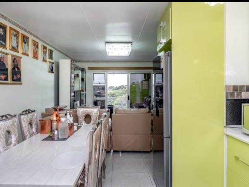 Open-plan living and dining area featuring high-gloss lime green kitchen cabinetry, tiled flooring, and direct access to a balcony through sliding glass doors.