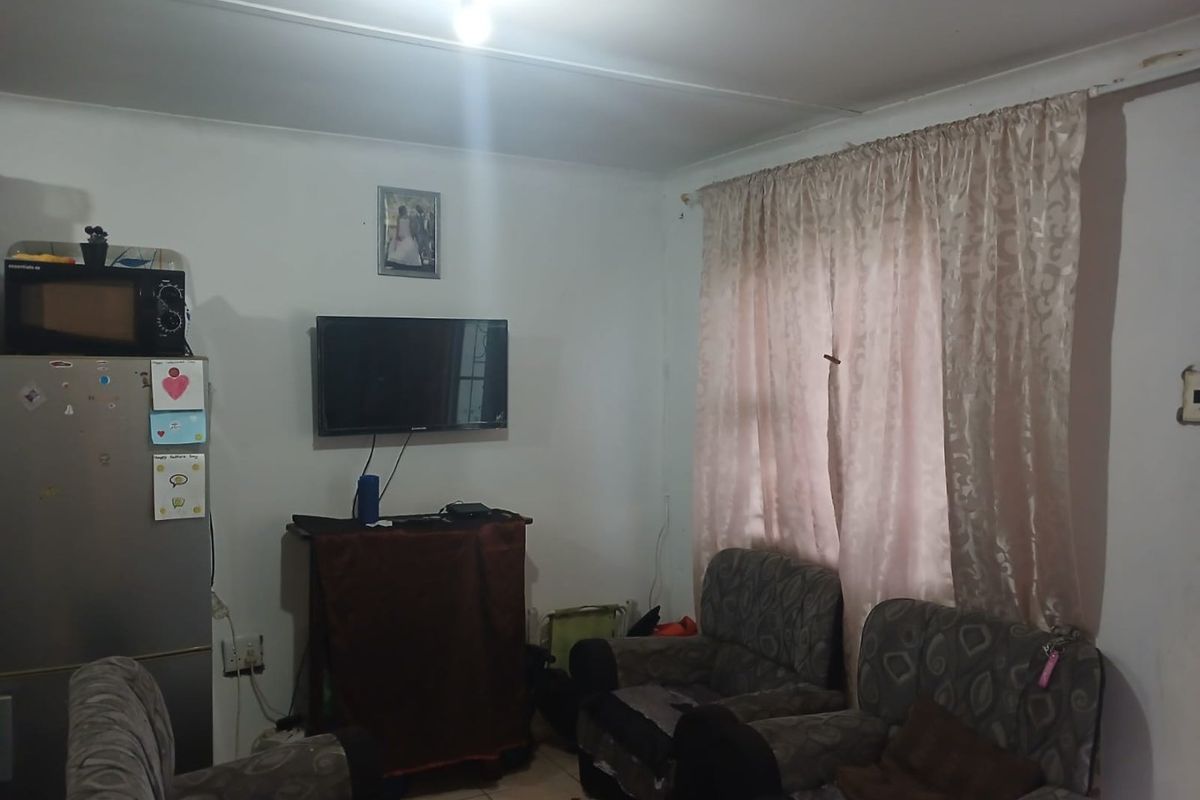 A functional living room space featuring tiled flooring and standard ceiling lighting, offering a blank canvas for potential interior updates and modernization.
