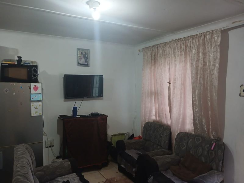 A functional living room space featuring tiled flooring and standard ceiling lighting, offering a blank canvas for potential interior updates and modernization.