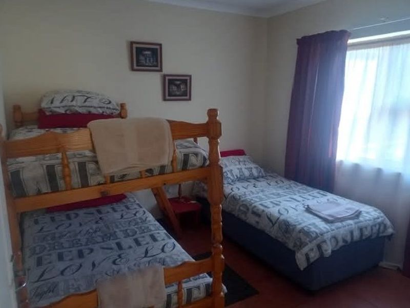 A functional bedroom featuring a window with curtain rails and tiled flooring, suitable for multiple occupants.