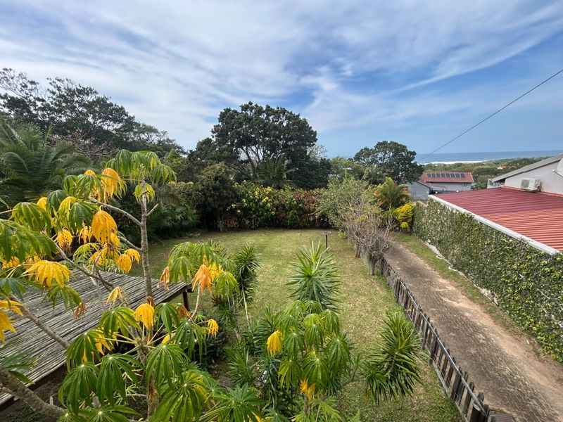 A spacious, well-maintained garden featuring a lush lawn, mature trees, and perimeter fencing, offering a peaceful outdoor setting.