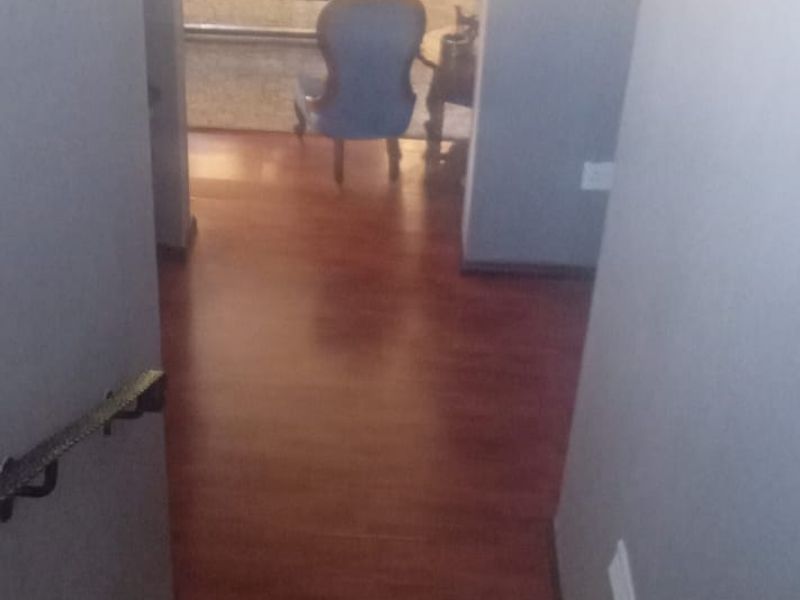 A view looking down a staircase with tiled steps leading to a lower level with laminate flooring and an adjacent living area.