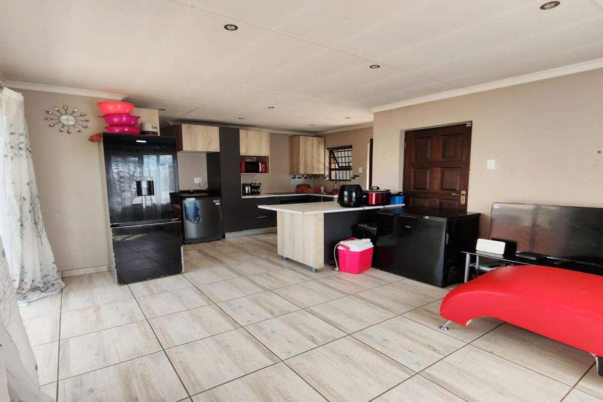 Open plan living and kitchen area featuring modern cabinetry, a central island, and neutral tiled flooring throughout the space.