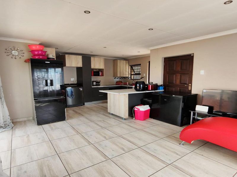 Open plan living and kitchen area featuring modern cabinetry, a central island, and neutral tiled flooring throughout the space.