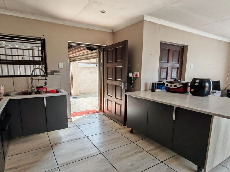 Kitchen featuring dark cabinetry, laminate countertops, tiled flooring, and direct access to an outdoor paved area.