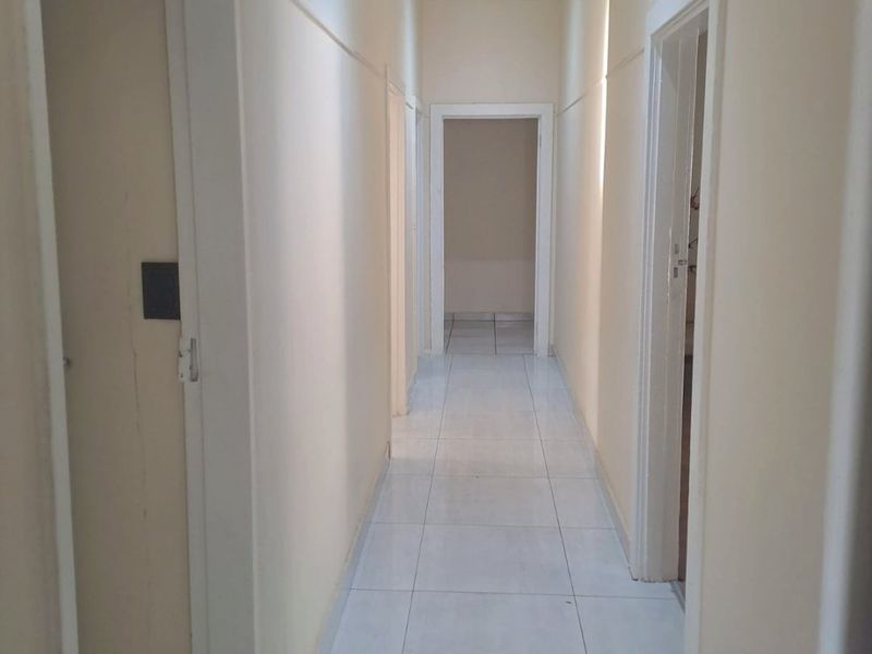 A clean, empty hallway featuring light-colored tiled flooring and neutral wall finishes, providing access to multiple rooms within the commercial property.
