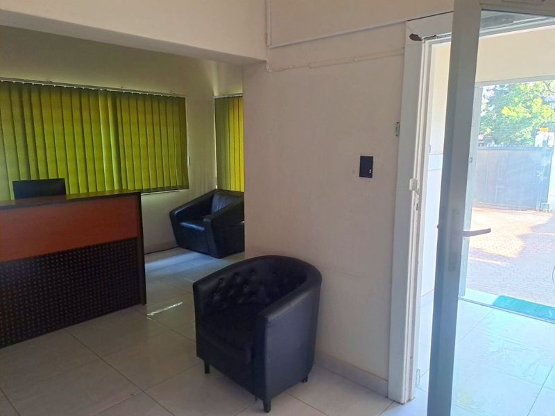 Commercial entrance area featuring tiled flooring, vertical blinds, and a glass door providing direct access to the exterior.