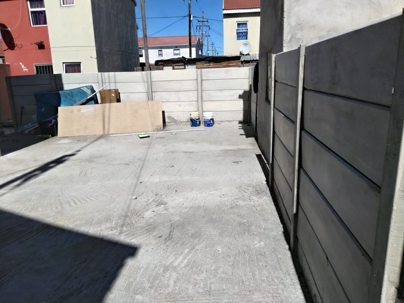 A rear outdoor area featuring a concrete slab and precast concrete boundary walls, offering a blank canvas for landscaping or outdoor improvements.