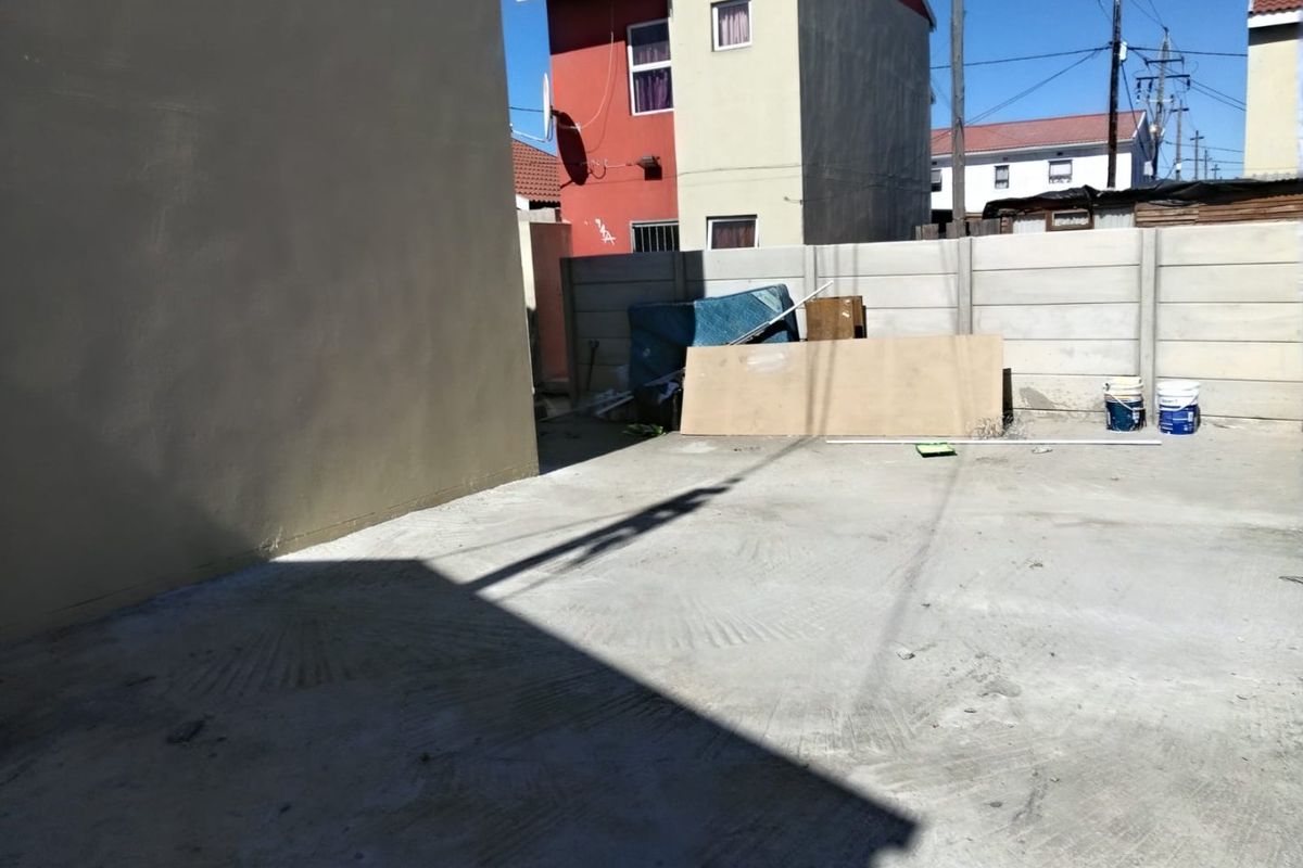 A paved rear yard area enclosed by a precast concrete boundary wall, offering a functional outdoor space.