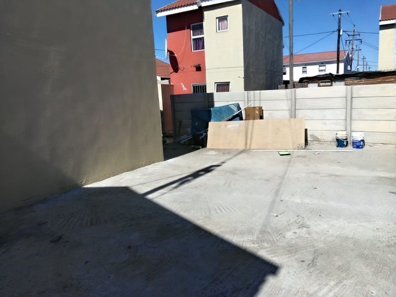 A paved rear yard area enclosed by a precast concrete boundary wall, offering a functional outdoor space.