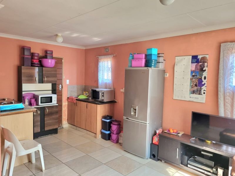 Open plan living and kitchen area featuring tiled flooring and built-in cabinetry, offering a functional layout with potential for cosmetic updates.