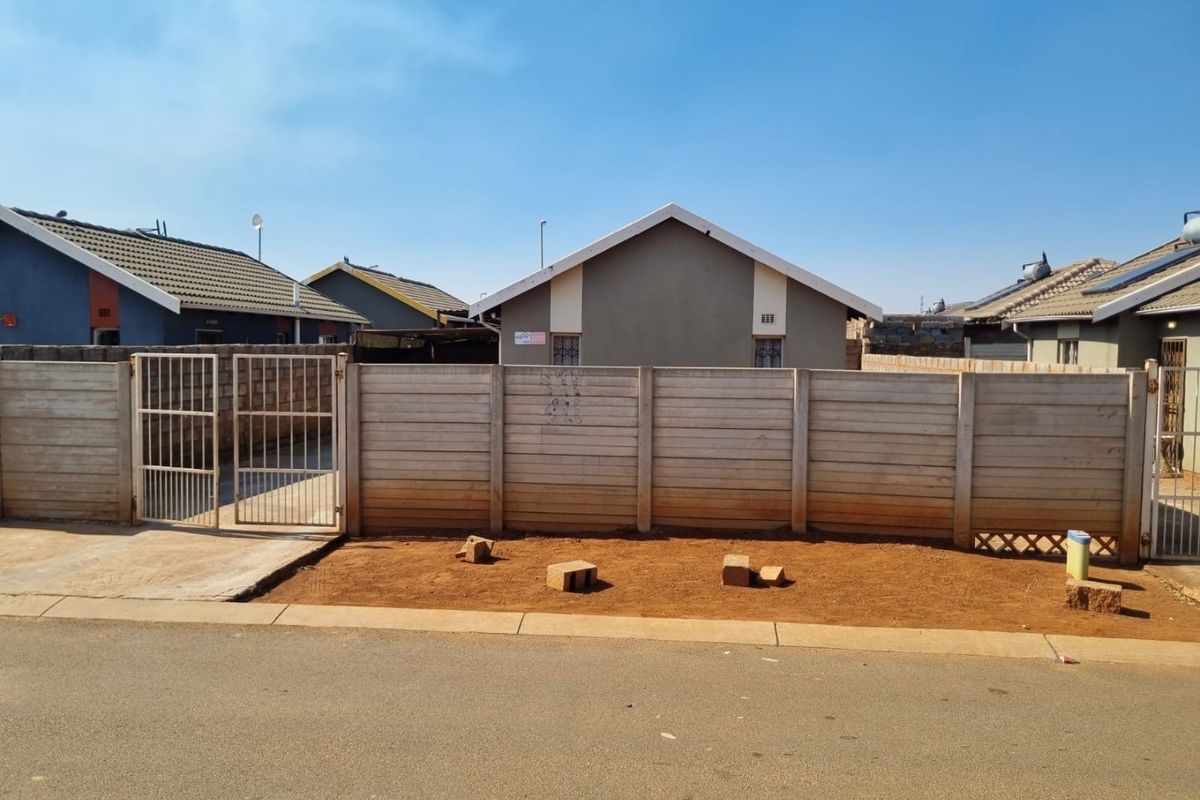Front view of a residential property featuring a precast concrete boundary wall, metal gate, and a tiled roof structure.