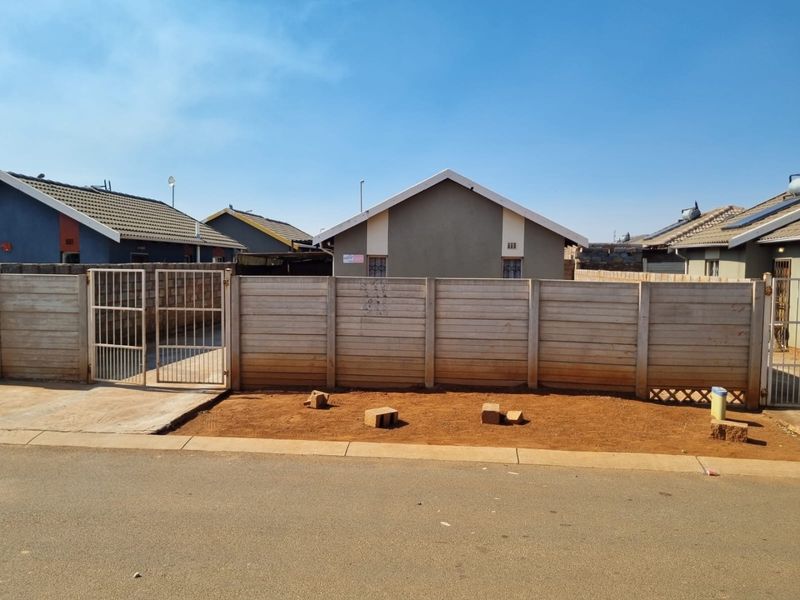 Front view of a residential property featuring a precast concrete boundary wall, metal gate, and a tiled roof structure.