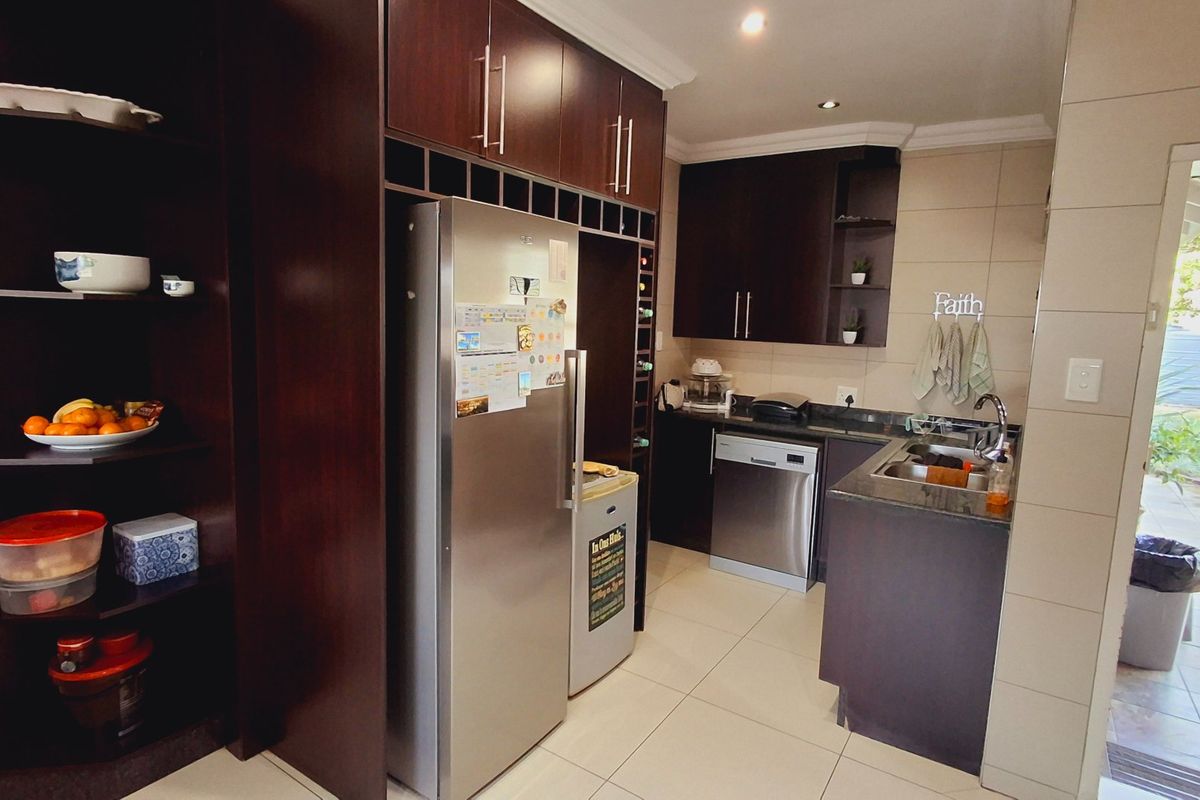 A functional kitchen featuring dark wood cabinetry, granite countertops, stainless steel appliances, and tiled flooring, with direct access to an outdoor patio area.