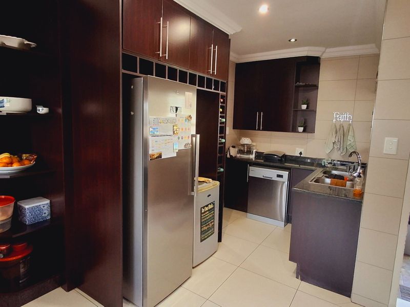 A functional kitchen featuring dark wood cabinetry, granite countertops, stainless steel appliances, and tiled flooring, with direct access to an outdoor patio area.