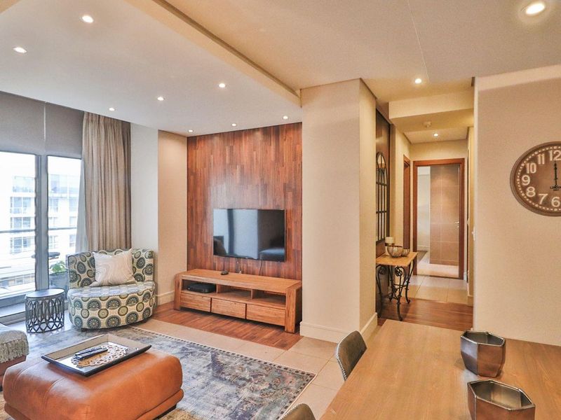 Modern open-plan living area featuring a wood-paneled feature wall, recessed downlighting, and direct access to a private balcony.